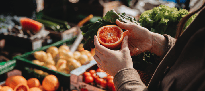 Person holding an orange at a farmers market